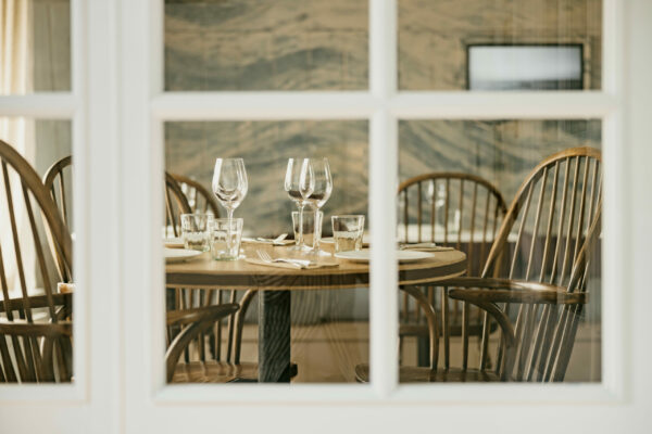 A dining room table at Fish Shop Ballater seen through a glass door, offering a glimpse of a cozy and inviting space to the seafood restaurant.