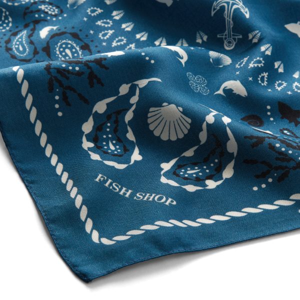 Close up corner of the fish shop branded neckerchief in blue white and navy shell and fish seaside theme design